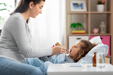 Image showing mother giving cough syrup to sick daughter