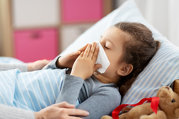 Image showing mother and ill little daughter blowing nose in bed