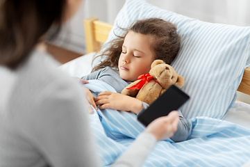 Image showing sleeping daughter and mother with phone at home