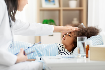 Image showing doctor with clipboard and sick girl in bed at home