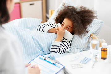 Image showing doctor and sick girl in bed blowing nose