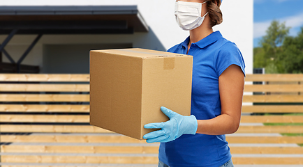 Image showing delivery woman in face mask holding parcel box