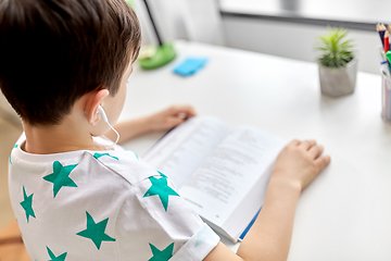 Image showing boy with earphones and textbook learning at home