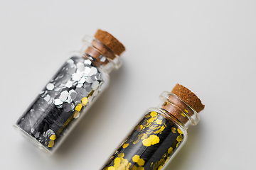 Image showing silver and gold glitter in bottles on white