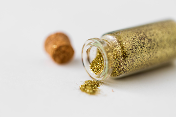 Image showing golden glitters poured from small glass bottle