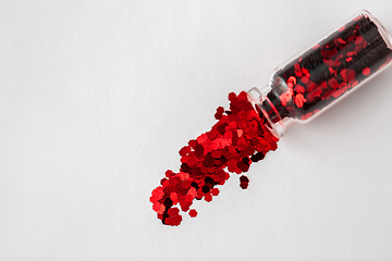 Image showing red glitters poured from small glass bottle