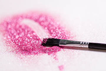 Image showing make up brush making stroke on pink glitters