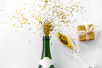 Image showing champagne bottle, glass, gift and golden glitters