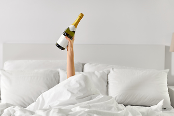 Image showing hand of woman lying in bed with champagne