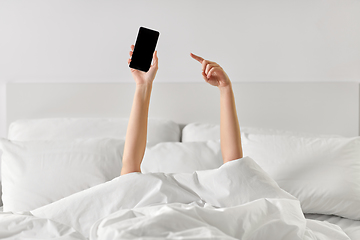 Image showing hands of woman lying in bed with smartphone
