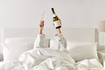 Image showing hands of woman lying in bed with champagne