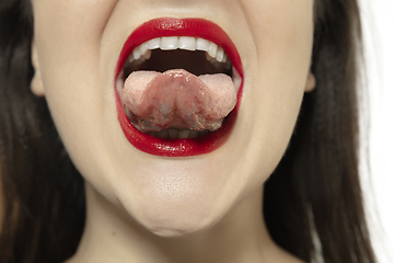 Image showing Smiling girl opening her mouth with red lips and showing the long big giant tongue isolated on white background, crazy and attracted, close up