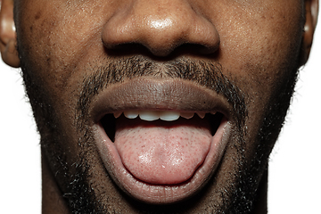 Image showing Close up of face of beautiful african-american young man, focus on mouth, stick out tongue