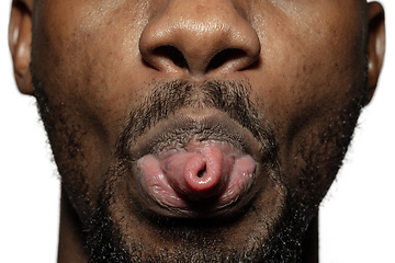 Image showing Close up of face of beautiful african-american young man, focus on mouth, stick out tongue