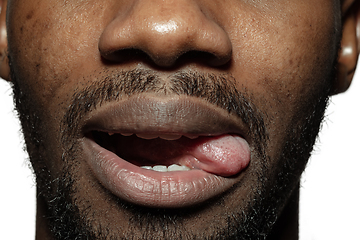 Image showing Close up of face of beautiful african-american young man, focus on mouth, stick out tongue