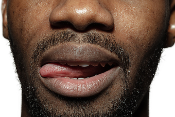 Image showing Close up of face of beautiful african-american young man, focus on mouth, stick out tongue