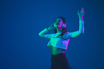 Image showing Caucasian woman\'s portrait isolated on blue studio background in pink-green neon light, stylish and beautiful