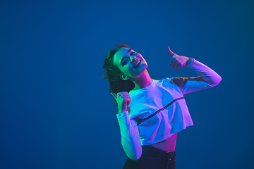 Image showing Caucasian woman\'s portrait isolated on blue studio background in pink-green neon light, stylish and beautiful