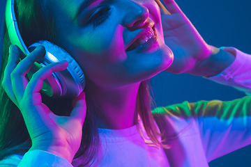 Image showing Caucasian woman\'s portrait isolated on blue studio background in pink-green neon light, stylish and beautiful, close up