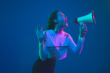 Image showing Caucasian woman\'s portrait isolated on blue studio background in pink-green neon light, stylish and beautiful