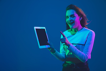 Image showing Caucasian woman\'s portrait isolated on blue studio background in pink-green neon light, stylish and beautiful