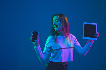 Image showing Caucasian woman\'s portrait isolated on blue studio background in pink-green neon light, stylish and beautiful