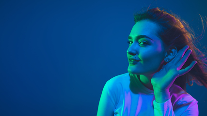 Image showing Caucasian woman\'s portrait isolated on blue studio background in pink-green neon light, stylish and beautiful