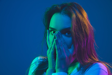 Image showing Caucasian woman\'s portrait isolated on blue studio background in pink-green neon light, stylish and beautiful