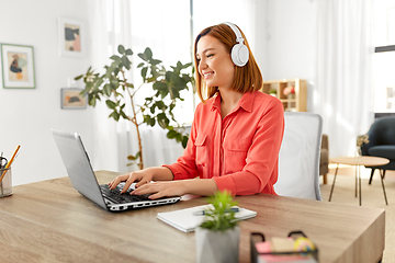 Image showing woman in headphones with laptop working at home