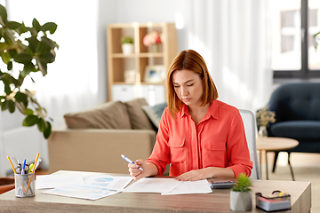 Image showing woman with calculator and papers working at home