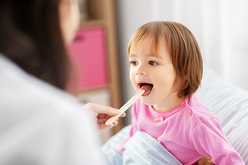 Image showing doctor checking sick girl's throat at home