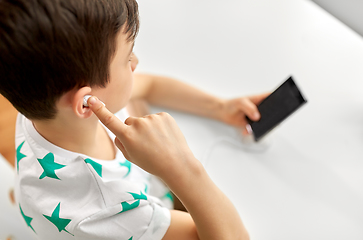 Image showing boy with earphones and smartphone at home