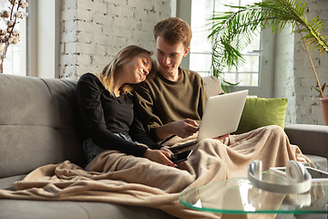 Image showing Attractive young couple using devices together, tablet, laptop, smartphone, headphones wireless. Gadgets and technologies connecting people all around the world