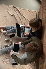 Image showing Attractive young couple using devices together, tablet, laptop, smartphone, headphones wireless. Gadgets and technologies connecting people all around the world. Top view