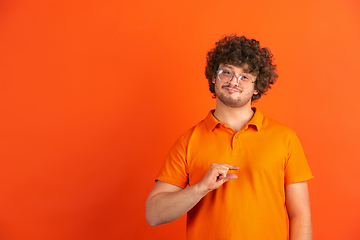 Image showing Caucasian young man\'s monochrome portrait on orange studio background