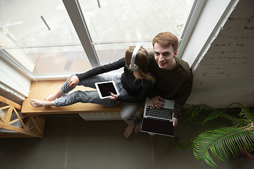 Image showing Attractive young couple using devices together, tablet, laptop, smartphone, headphones wireless. Gadgets and technologies connecting people all around the world. Top view