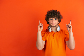 Image showing Caucasian young man\'s monochrome portrait on orange studio background