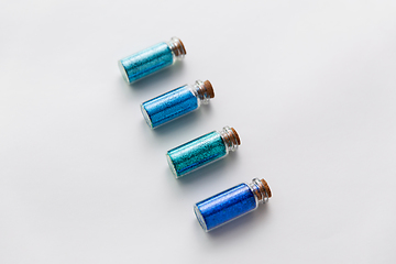 Image showing blue glitters in bottles over white background