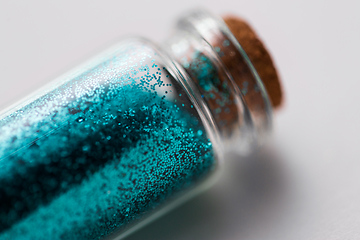 Image showing blue glitters in bottle over white background