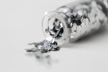 Image showing silver glitters poured from small glass bottle