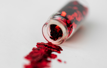 Image showing red glitters poured from small glass bottle