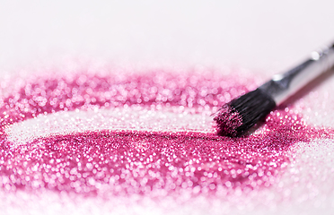 Image showing make up brush making stroke on pink glitters