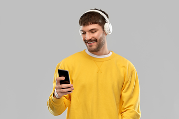 Image showing smiling young man with headphones and smartphone