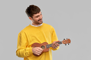 Image showing smiling young man playing ukulele guitar