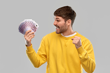 Image showing happy young man with money celebrating success