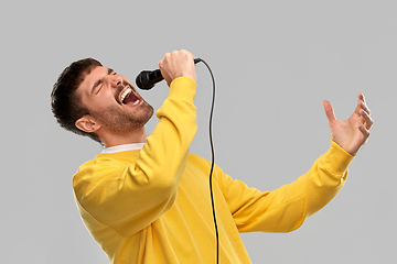 Image showing man in yellow sweatshirt with microphone singing