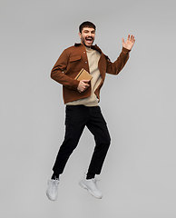 Image showing happy smiling young man with diary jumping in air