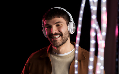 Image showing man in headphones over neon lights of night club