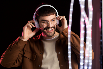 Image showing man in headphones over neon lights of night club