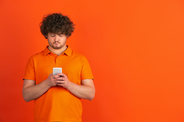 Image showing Caucasian young man\'s monochrome portrait on orange studio background